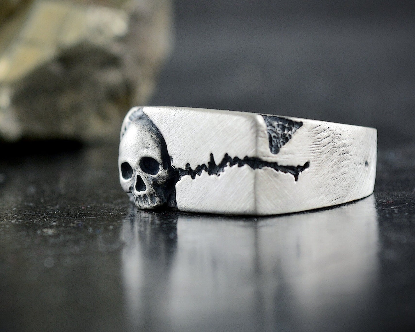 Anillo sello con textura de roca agrietada y una calavera
